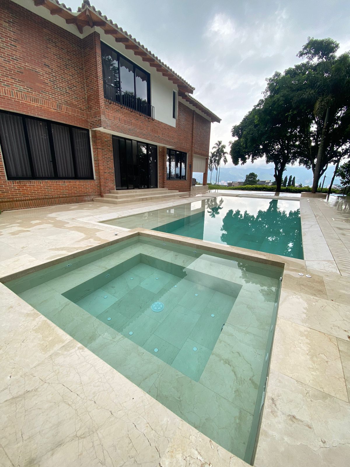 Piscina de forma libre con gresite azul y paisajismo integrado — proyecto Homeway Antioquia