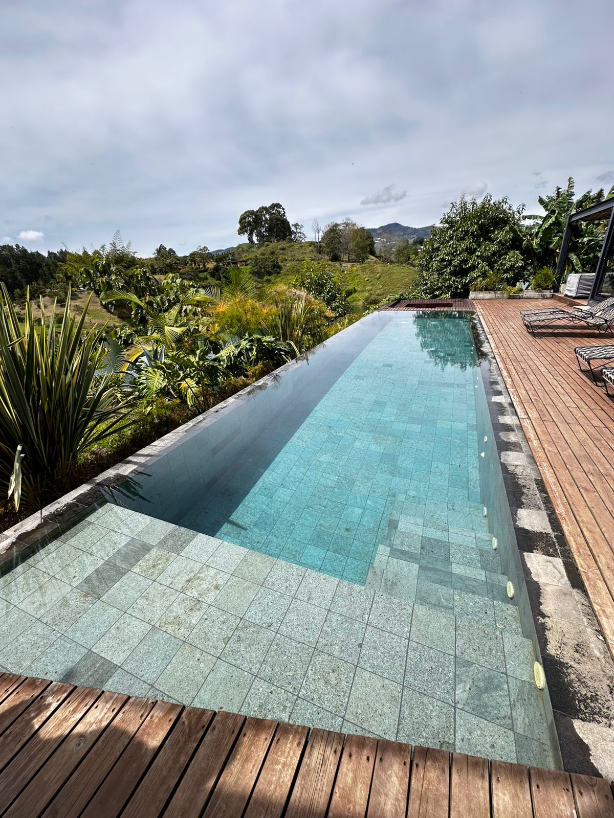 Piscina con gresite azul marino y escalinata en piedra natural — Homeway Colombia