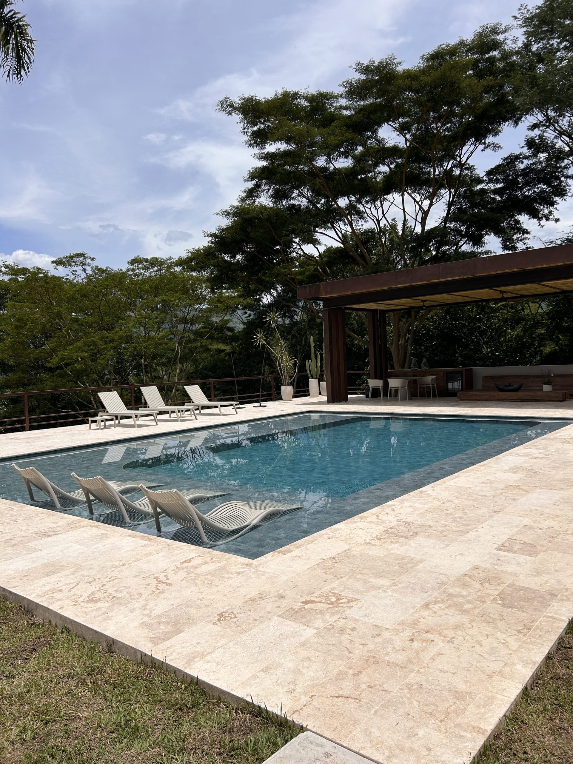 Piscina con fondo de gresite blanco y jardín tropical integrado — proyecto Homeway Colombia