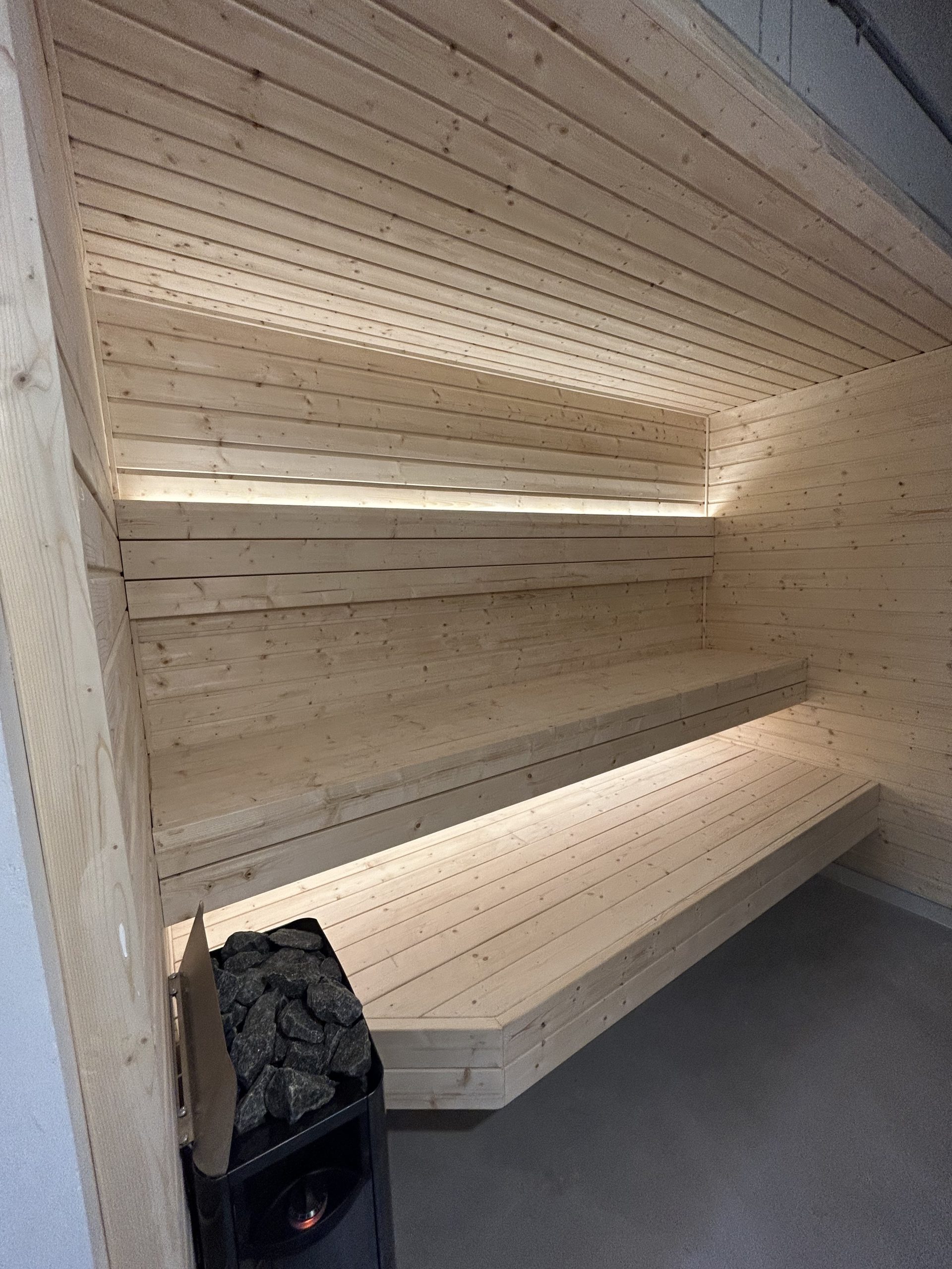 Interior sauna finlandesa tradicional con piedras de lava y calentador — proyecto Colombia Homeway
